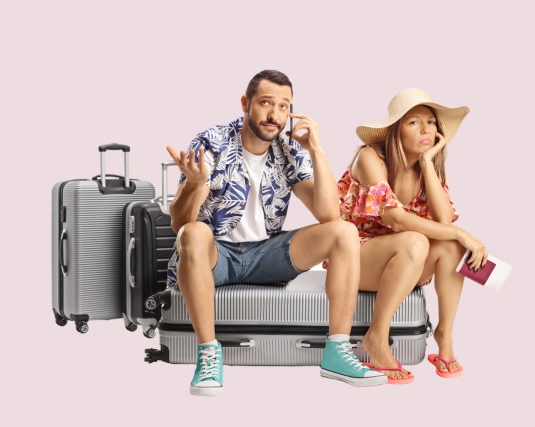 Stressed young couple sitting on a suitcase and using a smartphone.