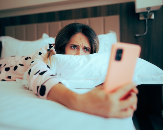 Worried Woman Looking at her phone Lying in Bed