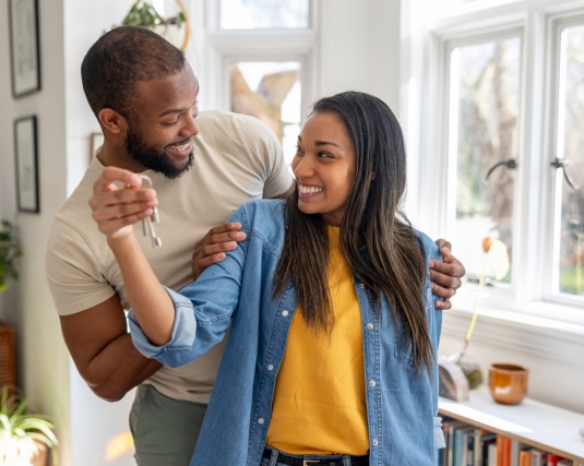 Young couple holding keys to their new house.