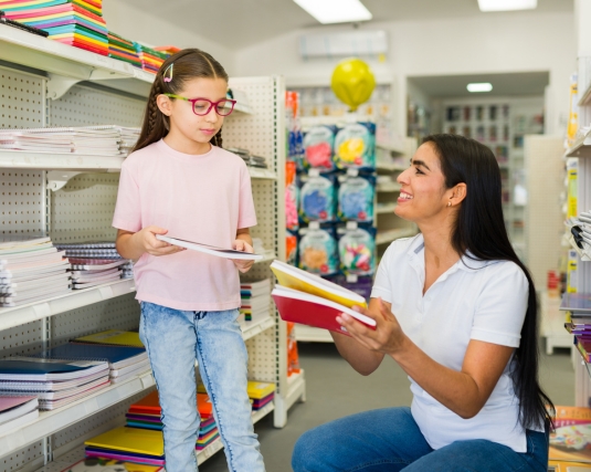 Latin female helping a little girl with her shopping in a school supplies store