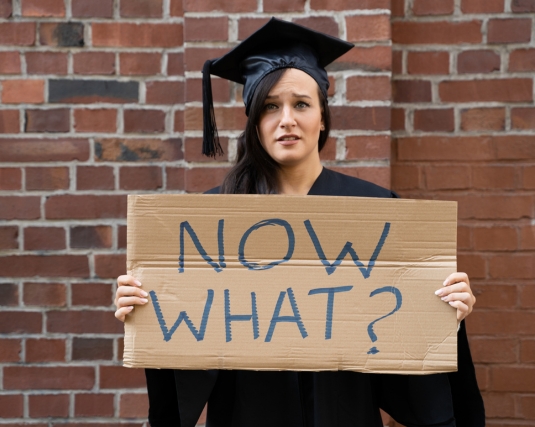 College graduate holding a sign that reads, 