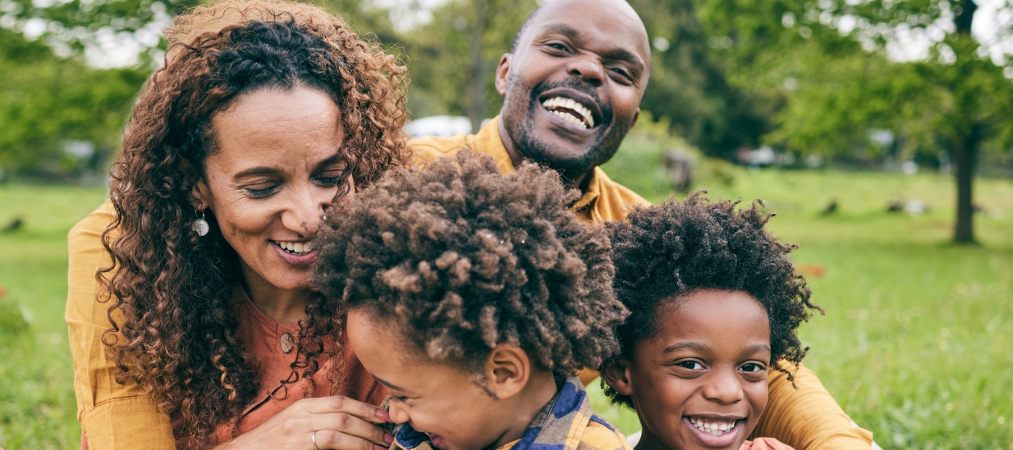 Happy black family, parents and children in a park in summer, smile and relax on grass field for love and fun in nature. Happiness, picnic and portrait of African people outdoor and playing together stock photo