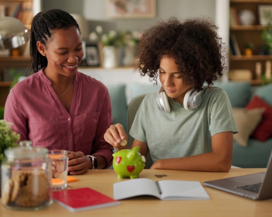 Mother and her teenage son saving money in piggy bank