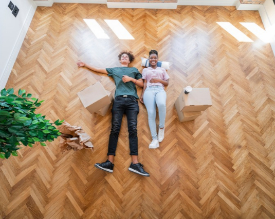 Young couple laying on floor of new house.