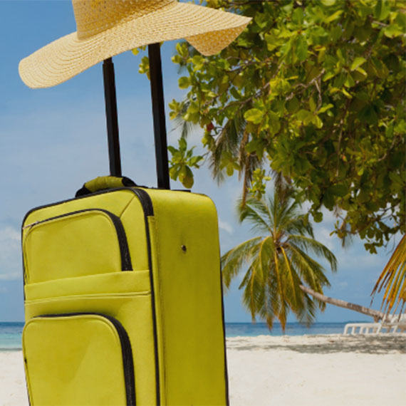 Green suitcase on a tropical beach