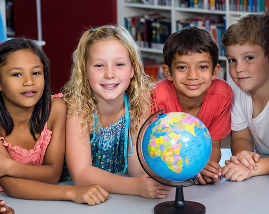 Children sitting behind a globe