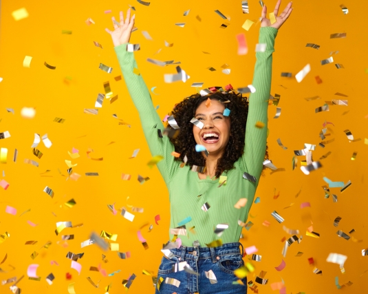 yellow background, happy excited young woman wearing glasses