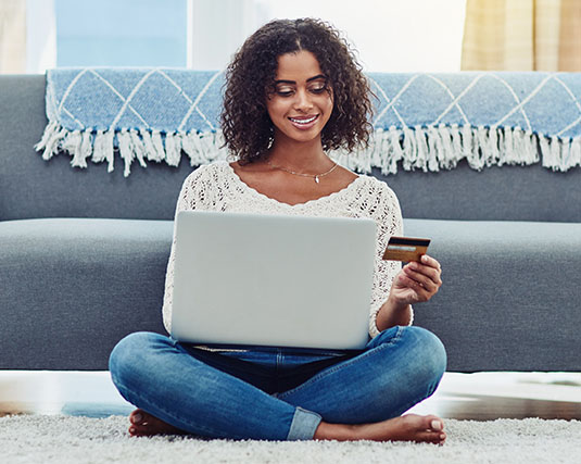 Woman sitting on floor using card to make online purchase