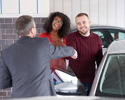 Couple shaking hands with a car dealer
