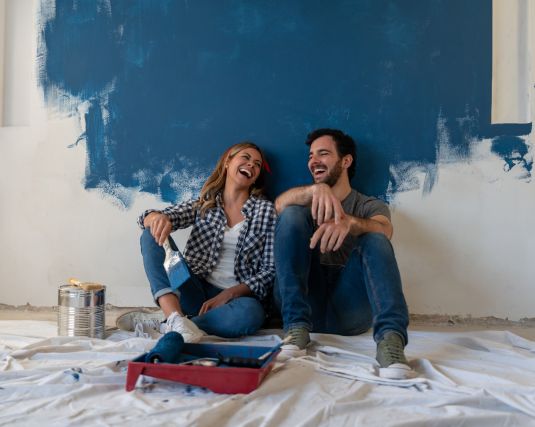Young couple laughing while painting a room.