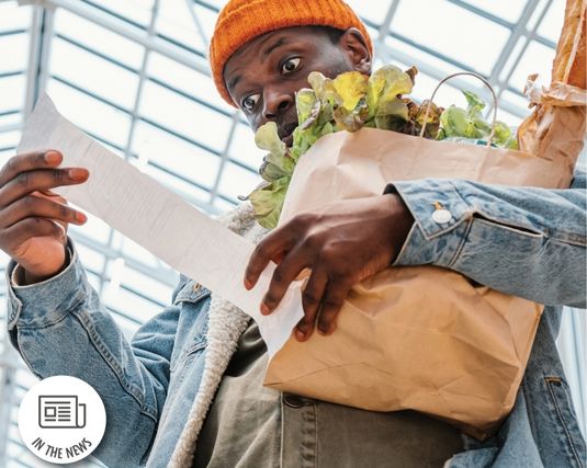 Young African-American man looking shocked at grocery receipt.