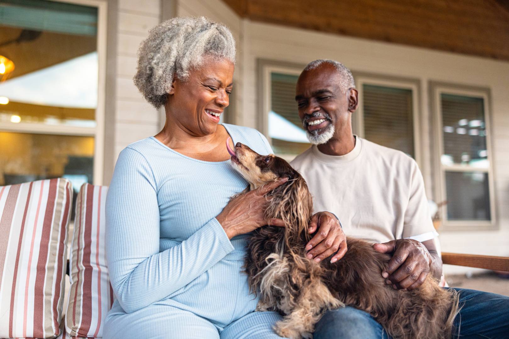 A smiling happy older retired couple playing with their dog
