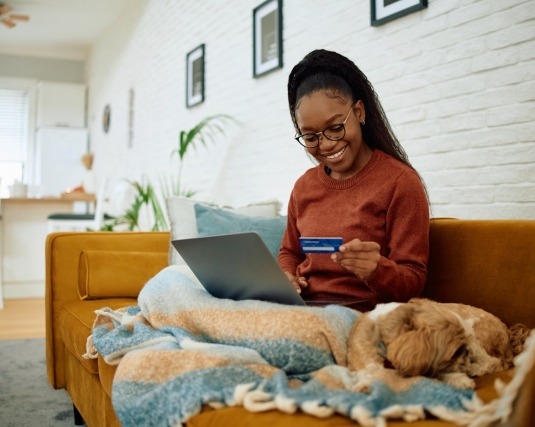 Happy woman using credit card and laptop while ordering on the internet.