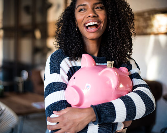 Young woman holding a pink piggy bank