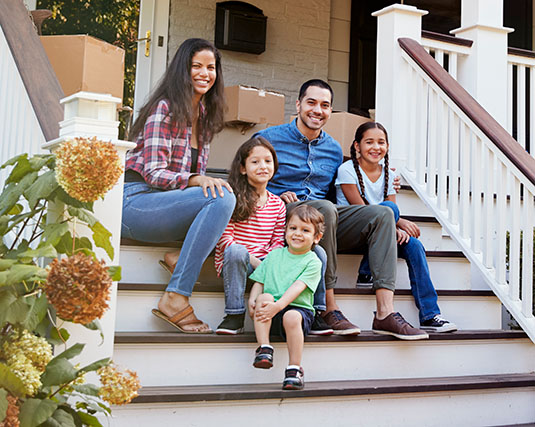 Family sitting on the front steps of their new home