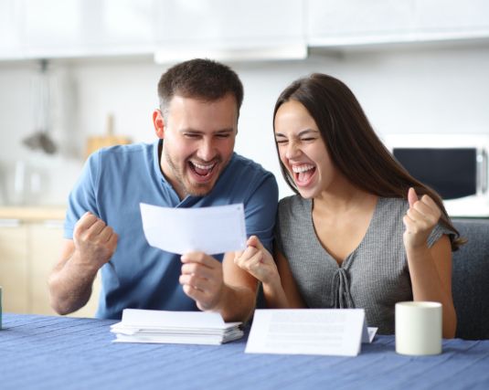 Excited couple checking tax return in the kitchen at home