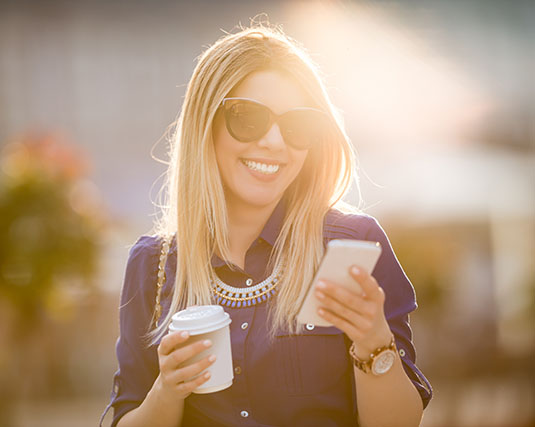 Woman on cell phone holding a coffee
