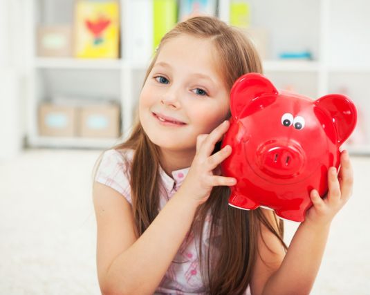 Young girl holding red piggy bank