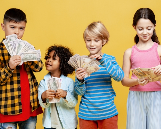 Young diverse children holding cash banknotes, learning about money, savings, and investments